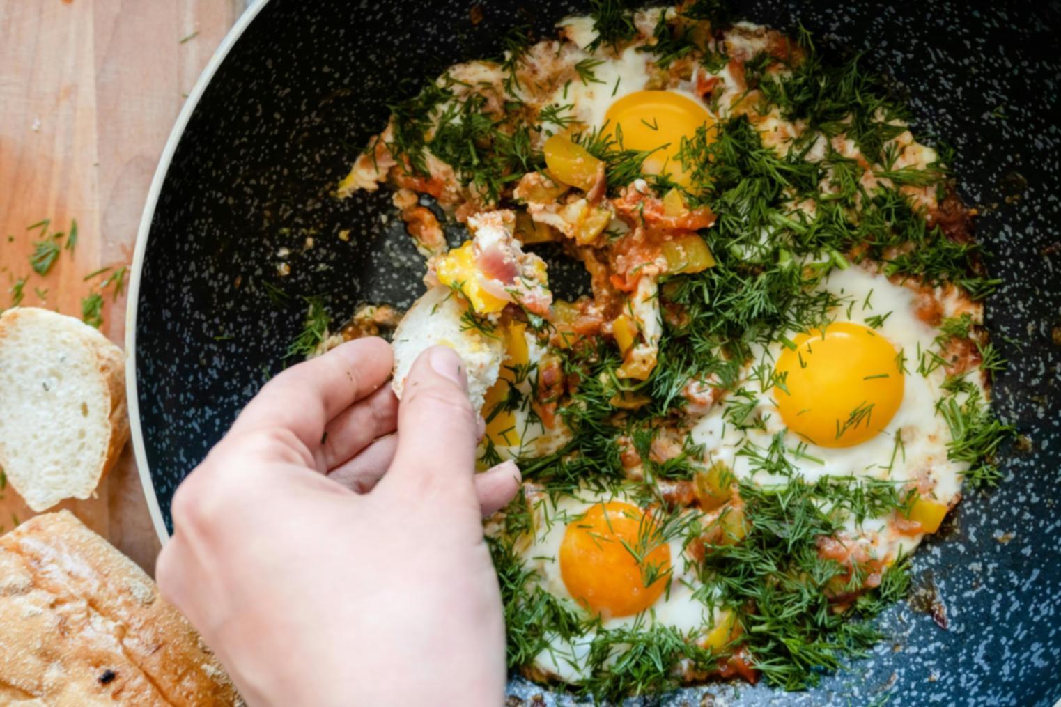 Close-up view of recipe testing process showing hands preparing ingredients with notebook for documentation